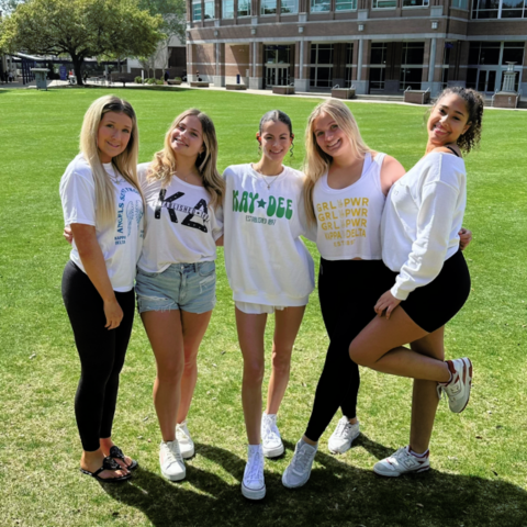 five girls standing on the green smiling and posing