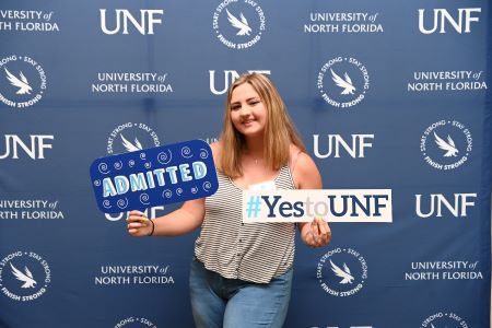 admitted student holding up yes to unf and admitted signs
