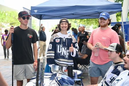 students standing in front of a tent smiling while wearing unf clothing