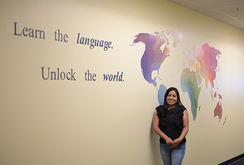 learn the language unlock the world student standing in front of a world map