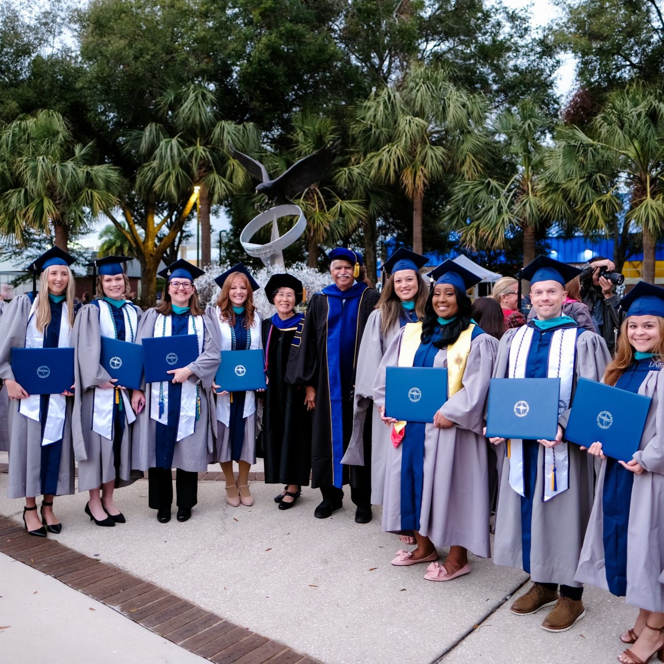 Health admin graduates standing in a group holding their diplomas