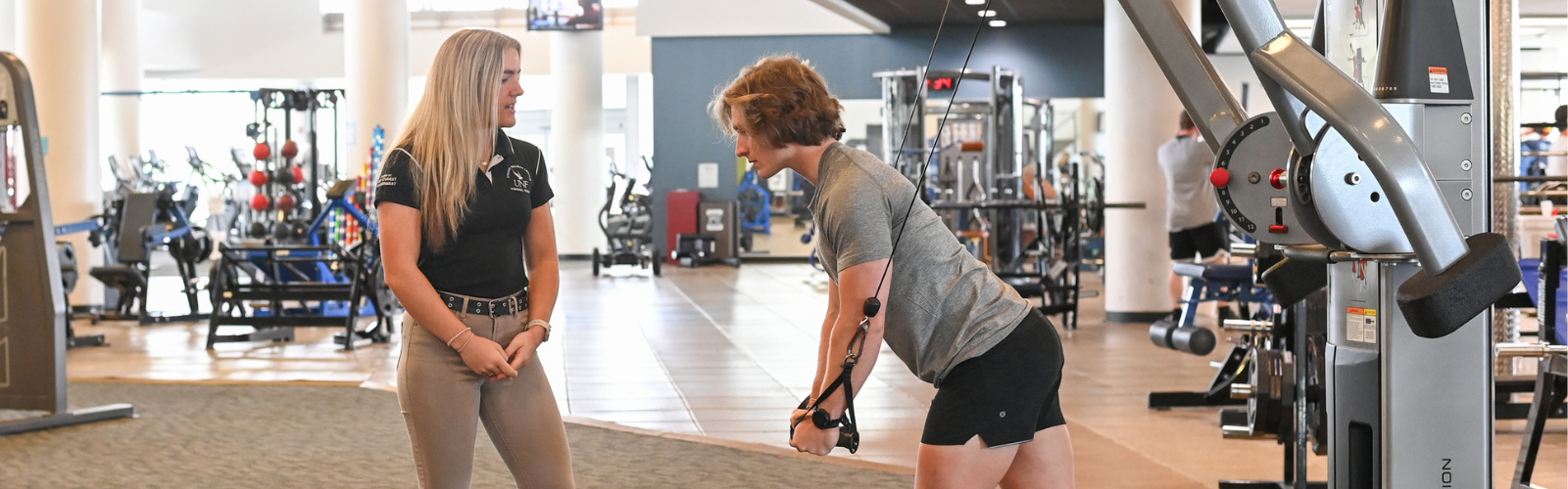 unf athletic trainer coaching student on weight machine