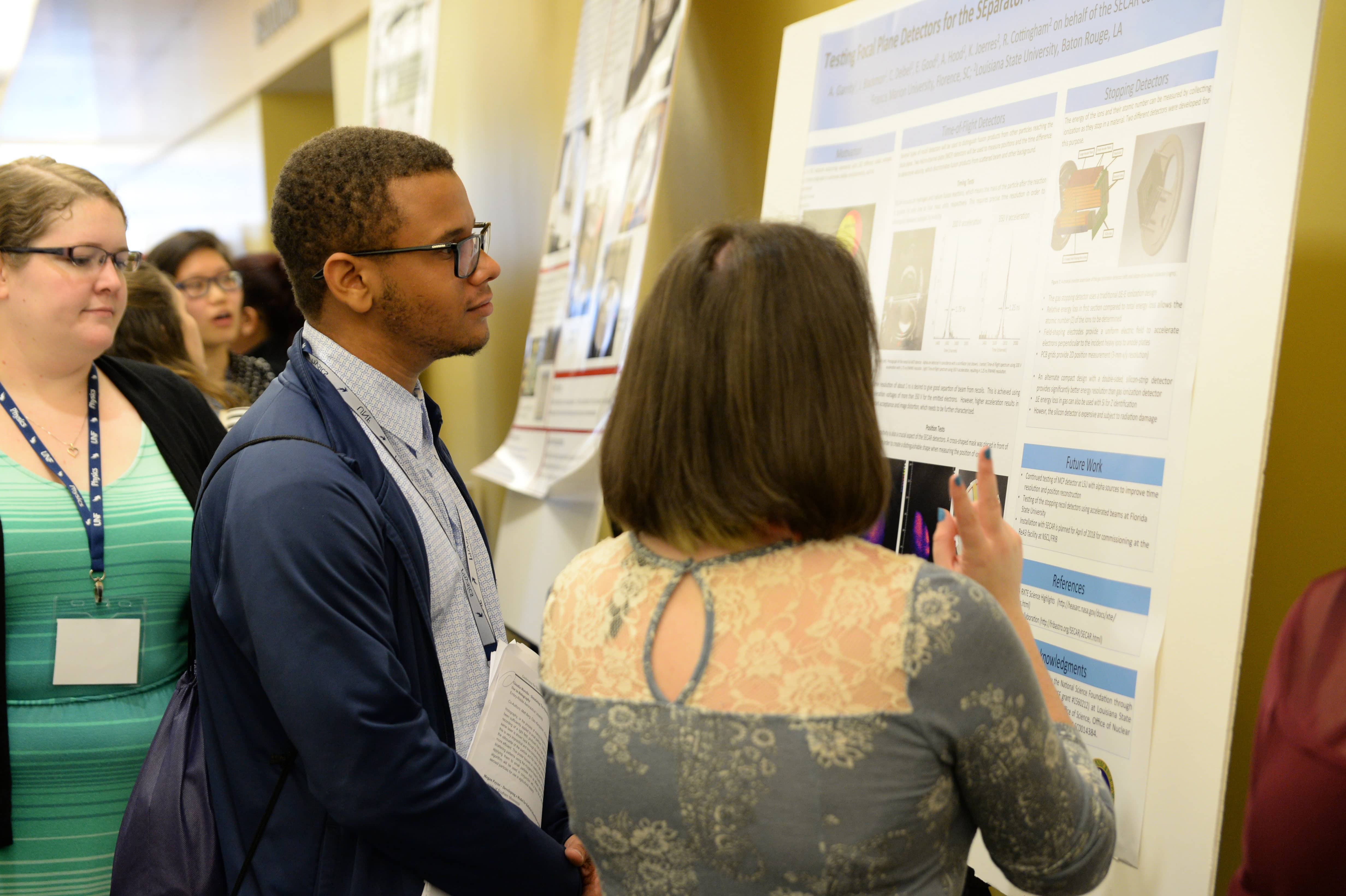 a student explaining a research poster