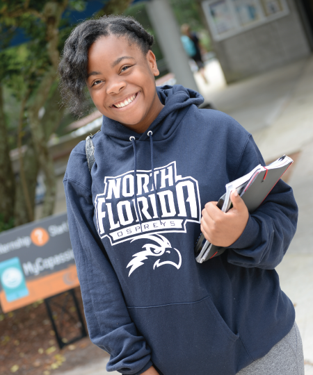 Student in UNF hoodie holding notebooks