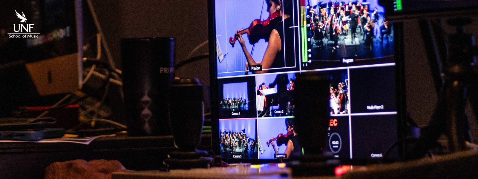 Stacked video monitors with images of orchestra players.
