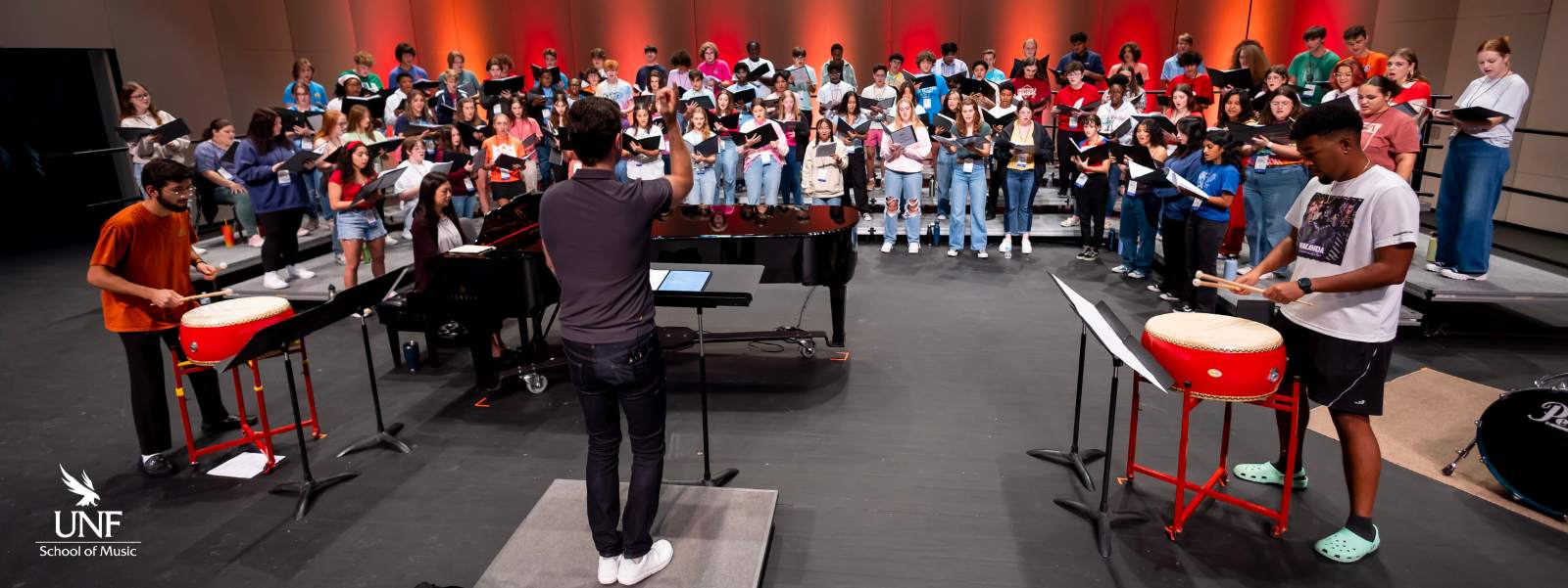 Conductor leading youth choir on stage
