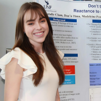 Grad student Natalie Clum smiling in front of her psychology poster presentation