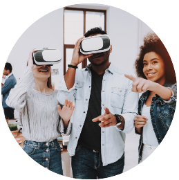 3 people standing together with 2 wearing virtual reality headsets and the third person pointing