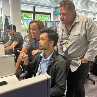 Ana and her peers engaged while looking at a computer screen inside a building at Wimbledon