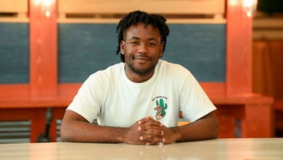 Damien Jackson smiling and sitting with his hands intertwined on a table