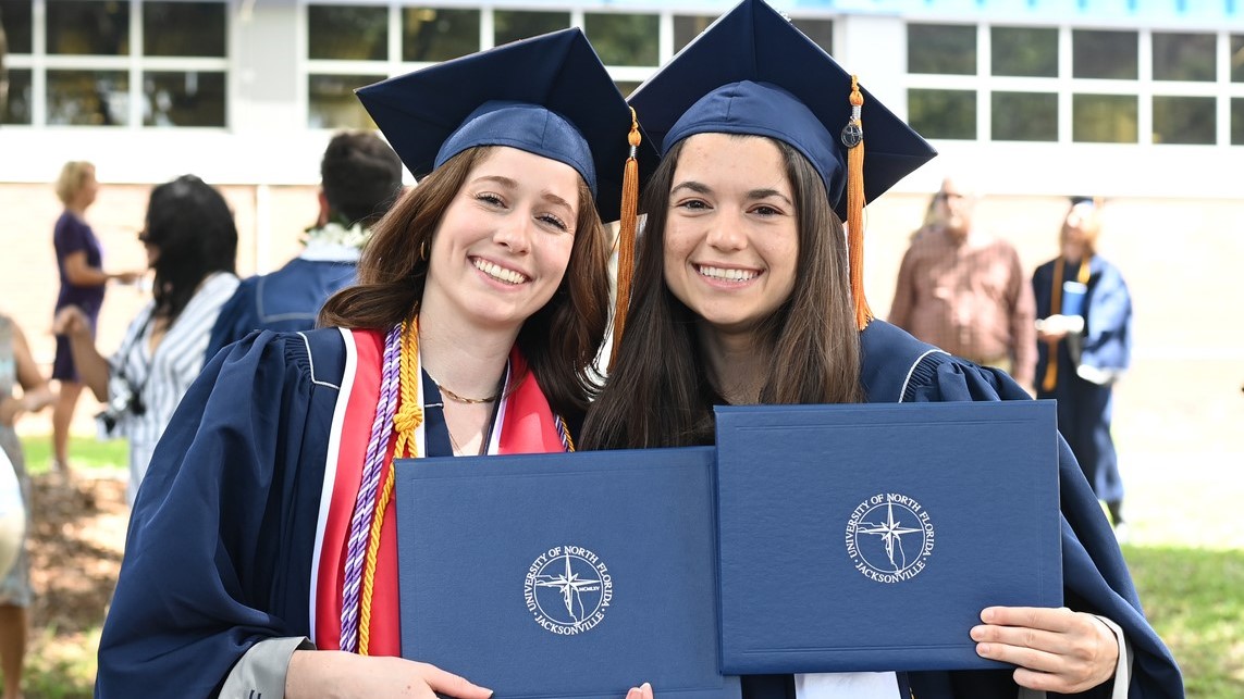 Two female graduates hold their diplomas after the ceremony.