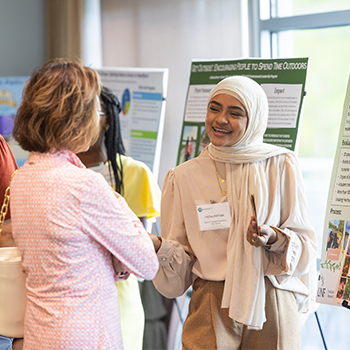 Two individuals conversing about a poster display.