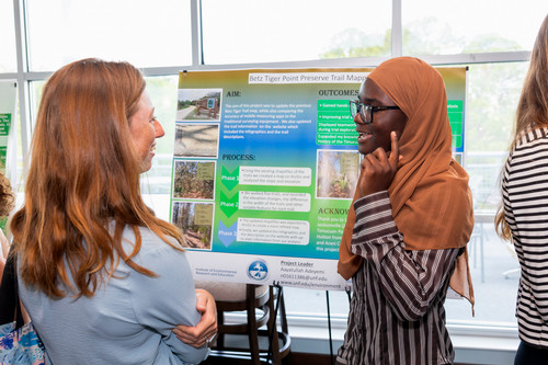 Student presenting poster to an event attendee.