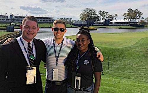 Three UNF interns with the Sports Management Program pose at the iconic Island Green Hole 17 at TPC Sawgrass.