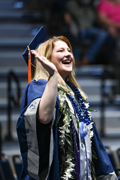 UNF student during spring 2024 graduation smiling and waving