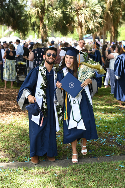 Two UNF graduates in cap and gown celebrate their graduation