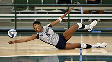 Mahalia White on the volleyball court diving for a ball