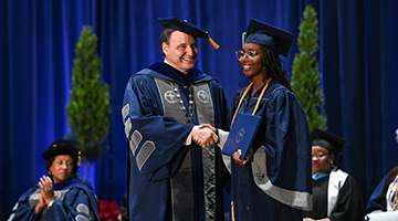 President Moez Limayem shaking hands with a student receiving her diploma