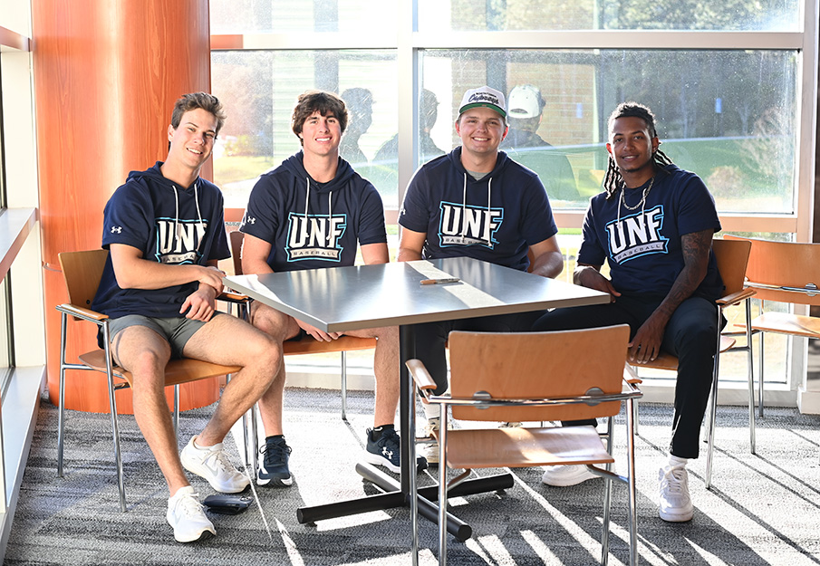 Four baseball players sitting at a table in the UNF Boathouse