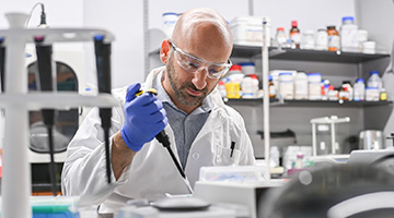 Dr. Bryan Knuckley in a lab putting a sample in a petri dish