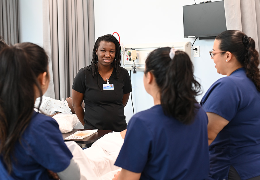 Nursing students surrounding a simulation with a professor