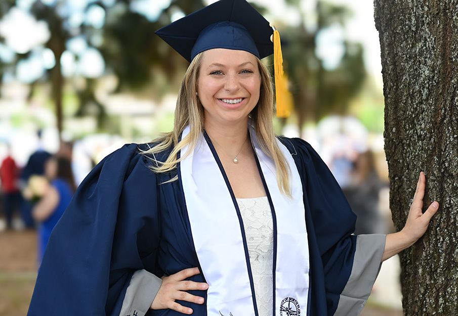 Mariah Glomb posed next to a tree in her cap and gown