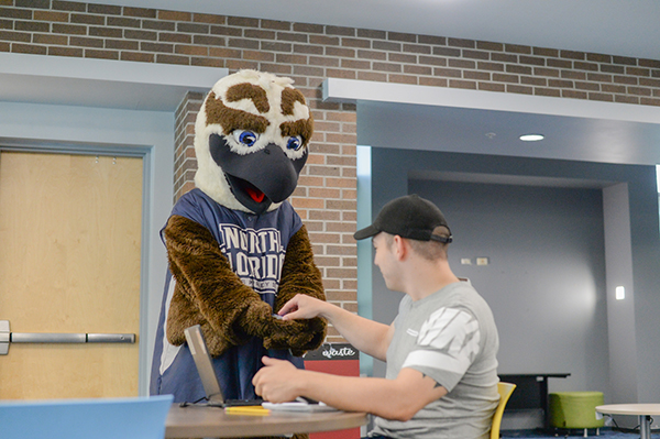 Ozzie osprey handing a sticker to a seated student