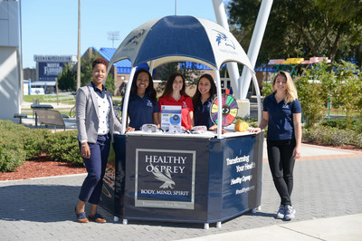 people posing for a picture at a Healthy Osprey stand on campus