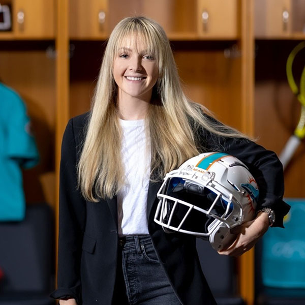 sarah holding a dolphins helmet in lockerroom