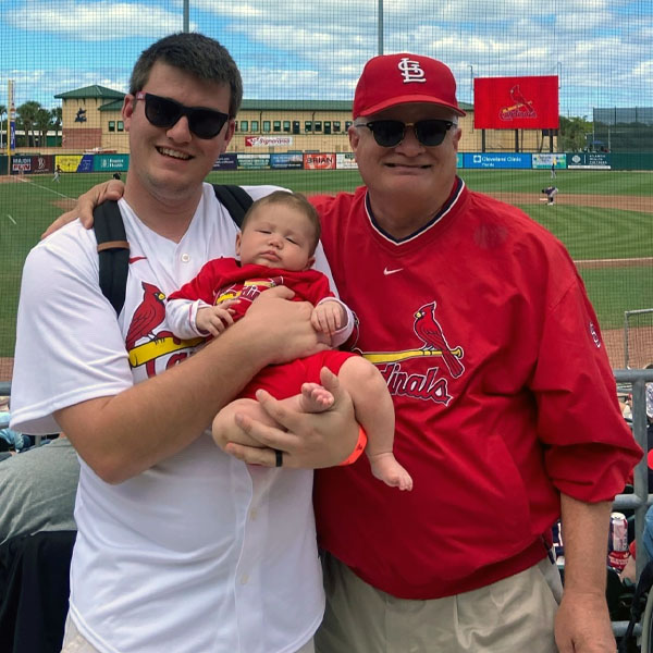 schneader holding a baby at a St. Louis game