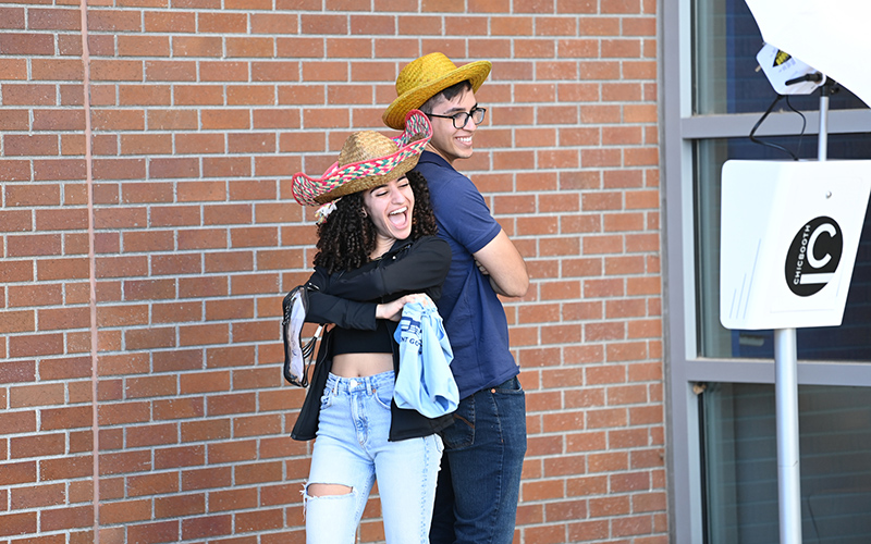 two students wearing hats and having fun posing for photos